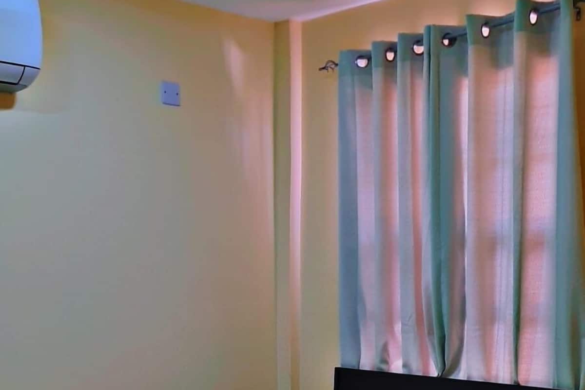 A hotel room with a bed, white bedding, a headboard, and a window with curtains.
