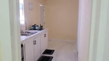 Un pasillo estrecho con un lavabo y armarios, que lleva a una habitación con una puerta.