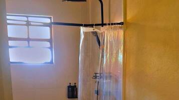 A bathroom with a shower, toilet, and a small sink area.