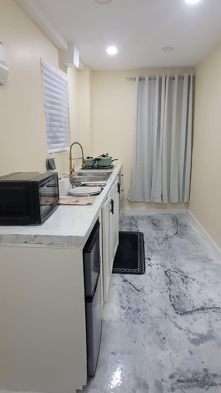 A compact kitchen with a microwave, sink, and gas stove.