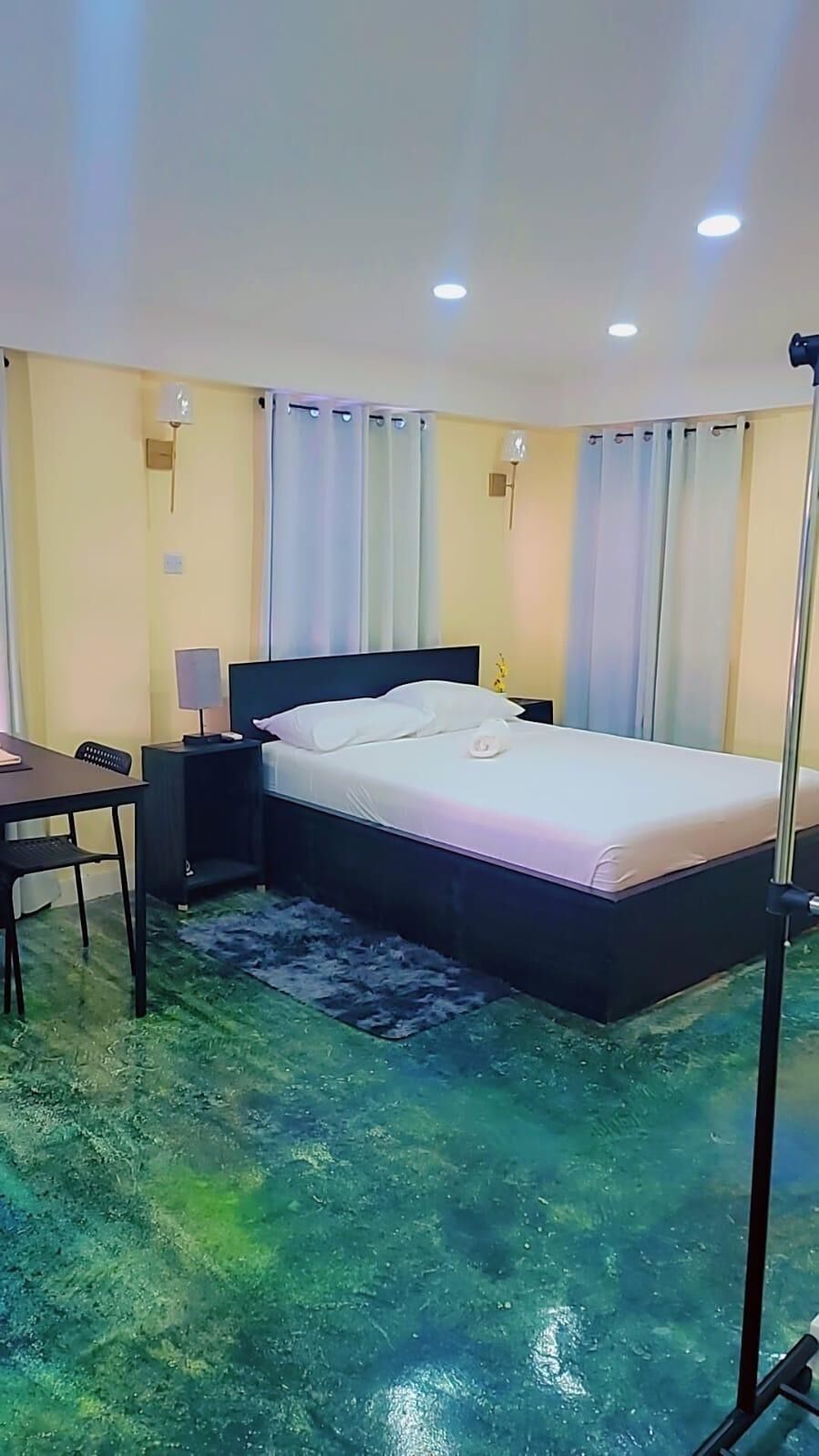 A bedroom with a bed, bedside tables, a desk, and a chair.
