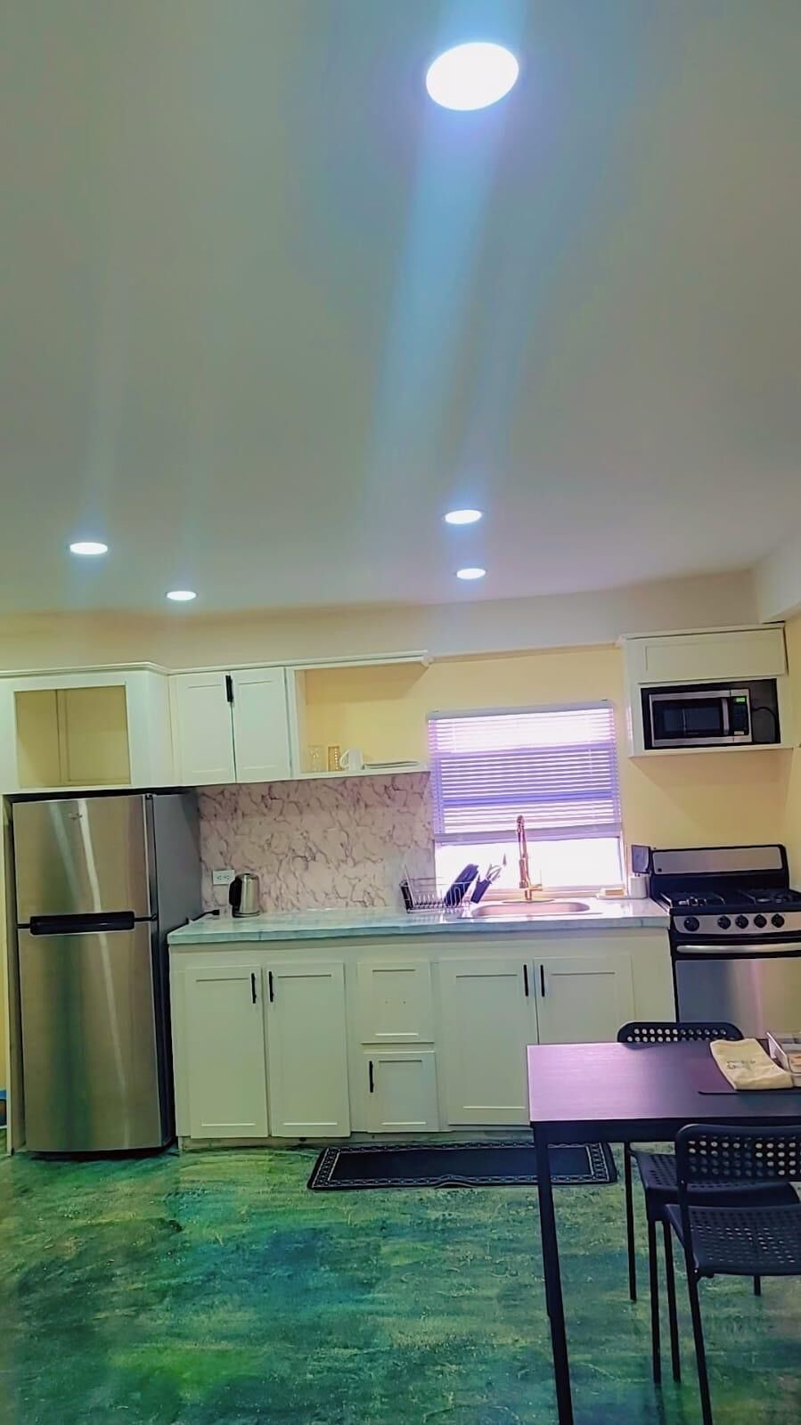 A kitchen with a refrigerator, stove, microwave, and sink.