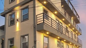 A multi-story residential building with balconies, a gated entrance, and a well-maintained lawn. - Oceanview Suites (St. George's)