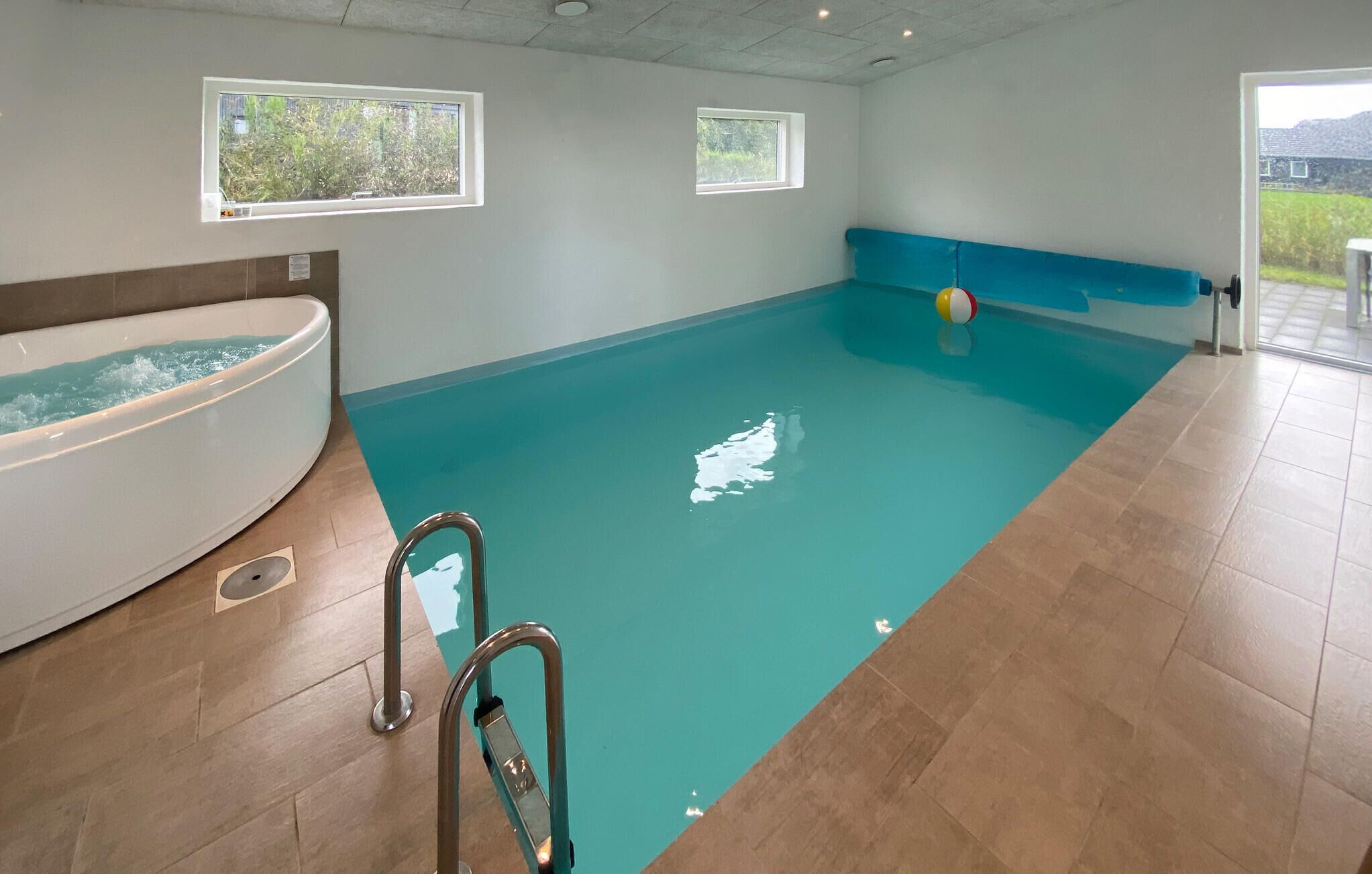 Une piscine avec un jacuzzi, deux fenêtres et une vue sur l’extérieur.