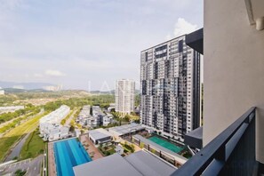 Un edificio de gran altura con varios balcones, una piscina y vistas a un paisaje verde.