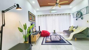 Un salon moderne avec un ventilateur de plafond, un canapé, un fauteuil poire, une table basse et un téléviseur.