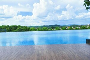 Una piscina al aire libre con una terraza de madera en primer plano y vistas a un paisaje verde y colinas al fondo.