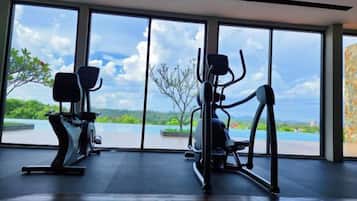 A gym with exercise equipment and large windows overlooking a scenic view.