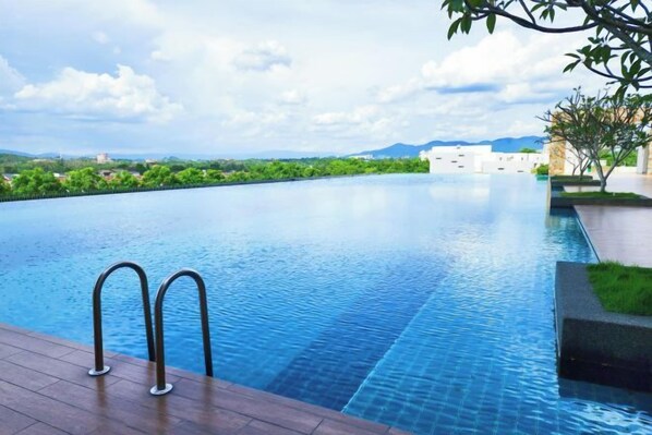 A swimming pool with a clear view of the landscape, a wooden deck, and a metal ladder. - KLIA Lili Residensi 5+2 PAX with Splendid Pool (Nilai)