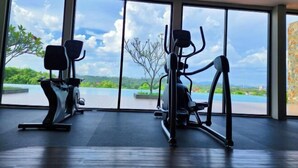 Une salle de sport équipée de deux appareils elliptiques et dotée d’une grande fenêtre offrant une vue sur un plan d’eau et la verdure environnante.