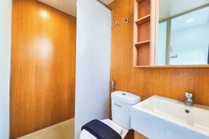 A bathroom with a wooden vanity, a white sink, and a toilet. - KLIA Lili Residensi 5+2 PAX with Splendid Pool (Nilai)