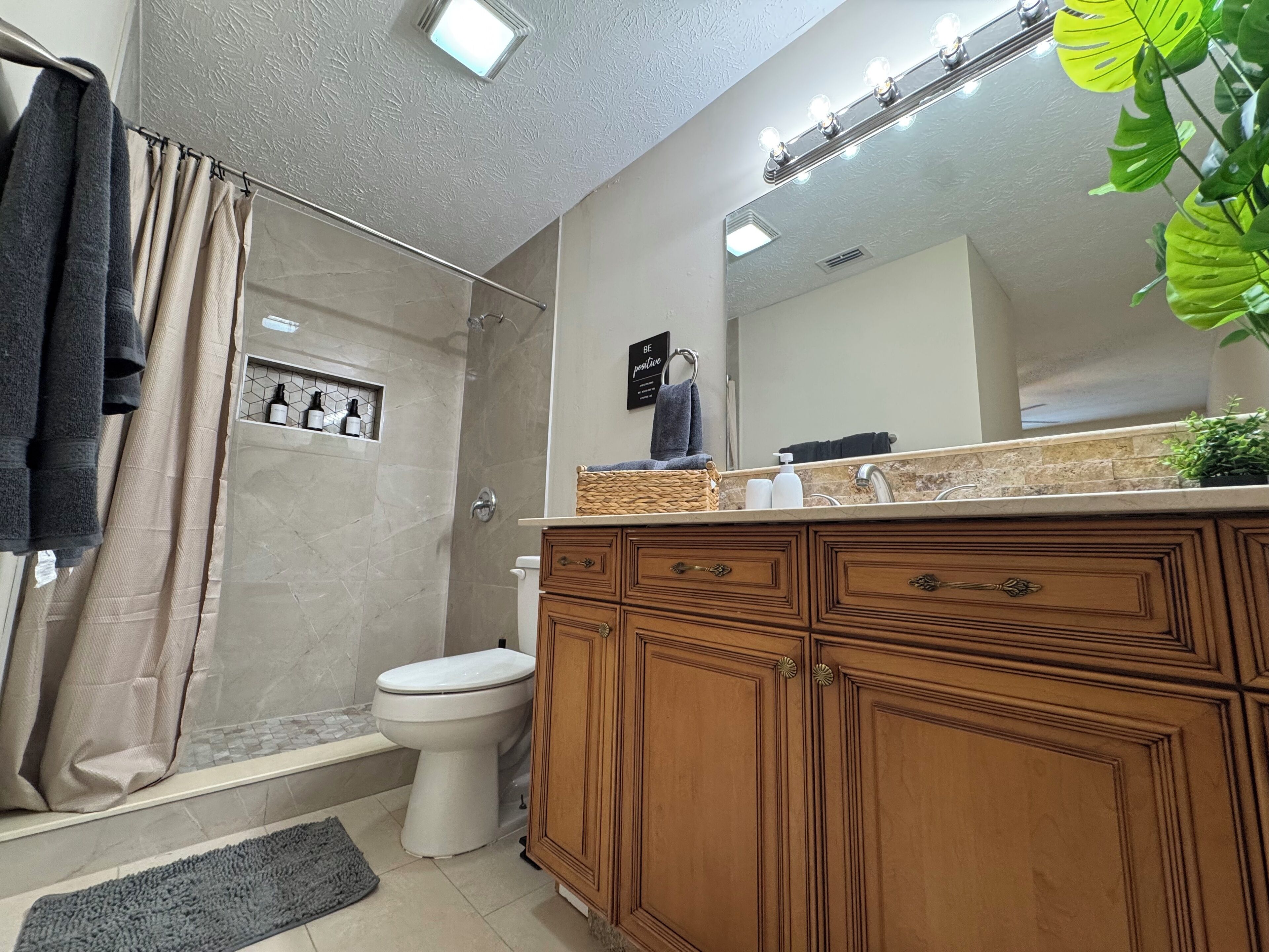 Un bagno con doccia, toilette, lavabo con specchio e lavandino.
