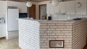 Una cocina moderna con armarios blancos, una isla integrada con textura similar al ladrillo e iluminación colgante.
