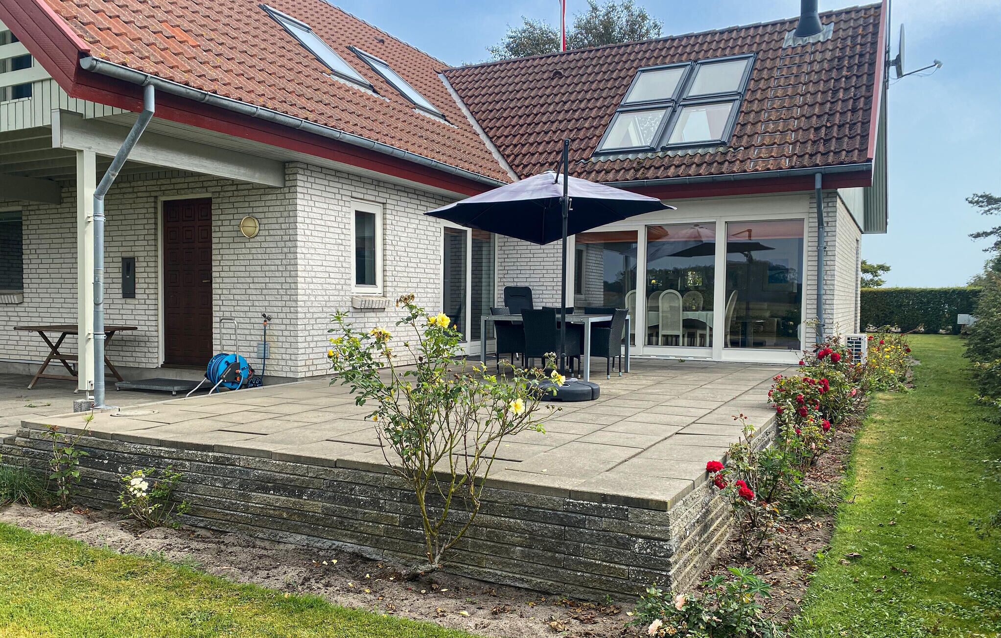 Une maison avec un patio, un coin repas et un jardin.