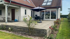 Una casa con un patio, un comedor y un jardín.