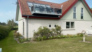 Una casa de dos pisos con techo rojo, balcón y fachada de ladrillo.