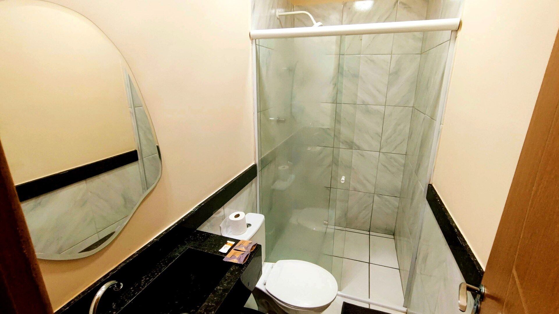 Une salle de bain compacte avec une douche à parois de verre, des toilettes et un lavabo avec un miroir.