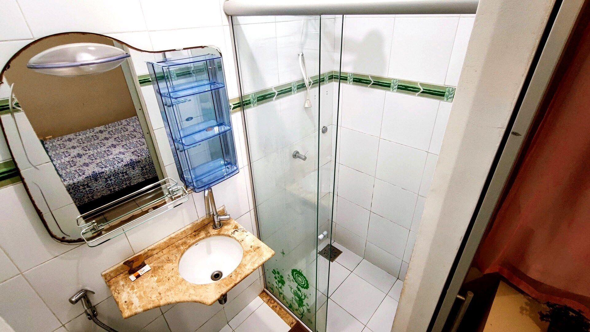 A bathroom with a sink, mirror, and shower.