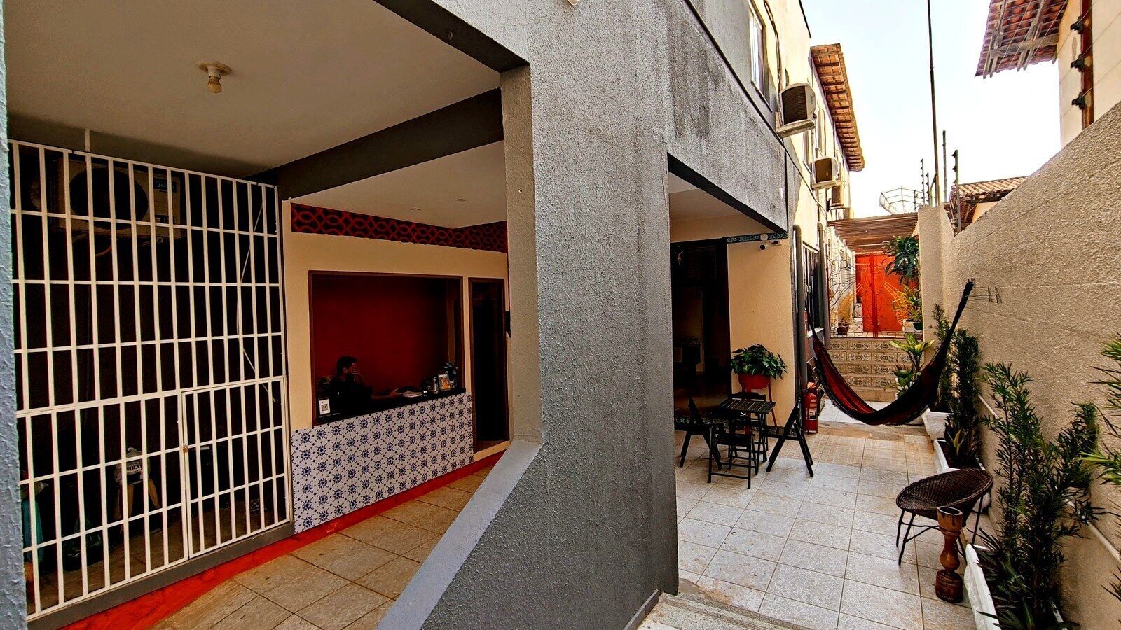 Un patio con zona de comedor, una hamaca y una entrada con reja.