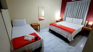 Habitación de hotel con dos camas, una mesita, un espejo y una ventana con cortinas.