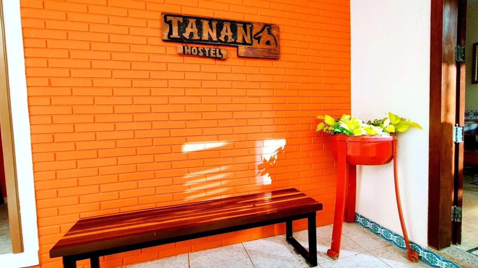 A hostel with a brick wall and a wooden bench.