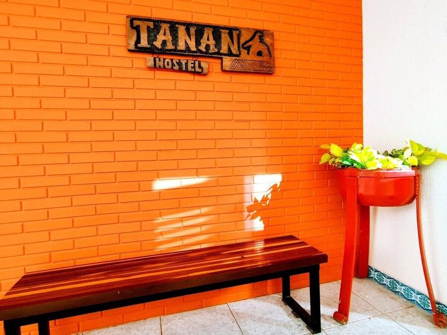 A hostel with a brick wall and a wooden bench.