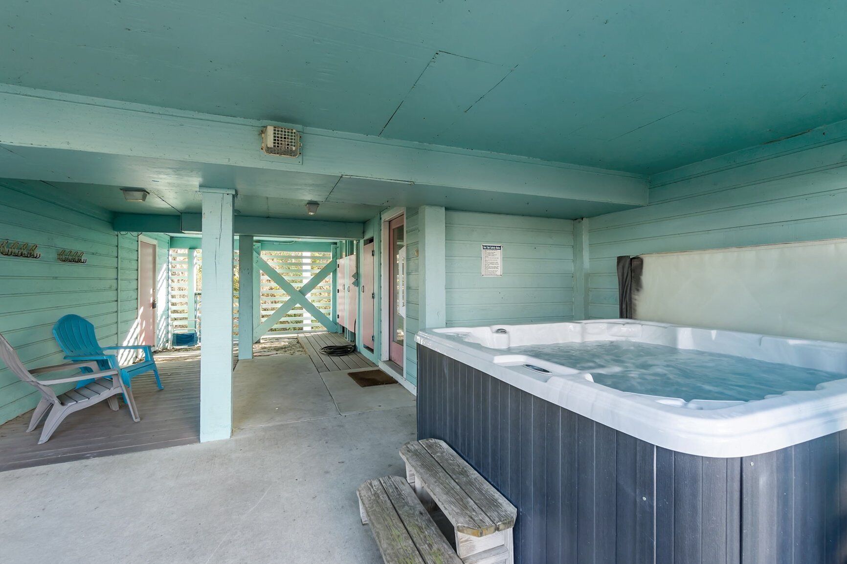 Una habitación con un jacuzzi, sillas de madera y un banco de madera.