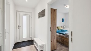 Ein modernes Schlafzimmer mit einem Bett, einem Holzschrank, einer Bank und einer Tür zu einem anderen Raum.