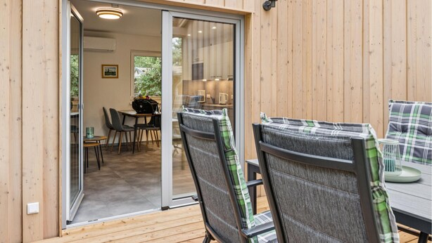 Eine Holzterrasse mit Essbereich, inklusive Stühle und Tisch.