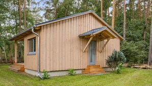 Eine Holzhütte mit geneigtem Dach, einer Haustür und einer kleinen Veranda mit Stufen.
