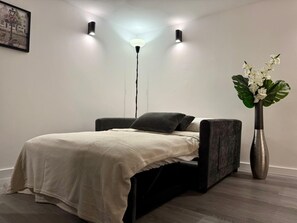 A modern bedroom with a bed, a floor lamp, and a vase with flowers.