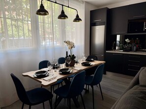 A modern kitchen with a built-in microwave, a refrigerator, and a dining area with a wooden table and blue chairs.