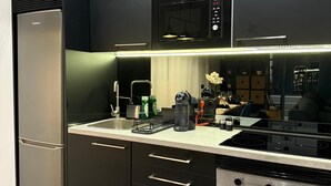 Una cocina moderna con armarios negros, horno empotrado y microondas.