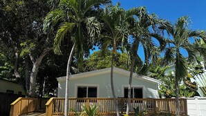 A white house with a wooden deck and a small staircase leading to a porch.