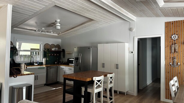 A modern kitchen with a central island, white cabinetry, and a wooden dining table with chairs.