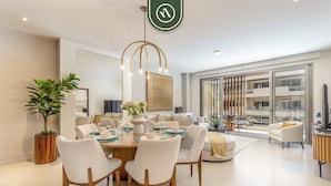 Un espace repas moderne avec une table ronde pour six personnes, entourée de chaises blanches à revêtement rembourré.