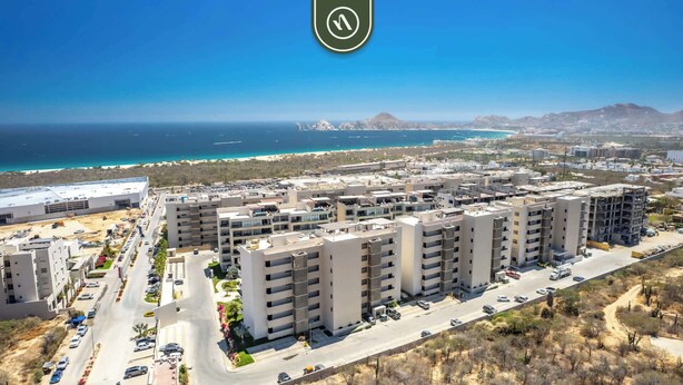 Un ensemble immobilier résidentiel de grande hauteur, doté de nombreux balcons, d’un espace de stationnement et offrant une vue sur la côte.