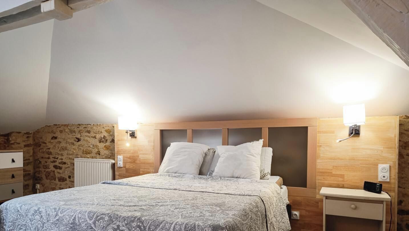 A bedroom with a wooden headboard, a bed with patterned bedding, a nightstand, and a radiator.