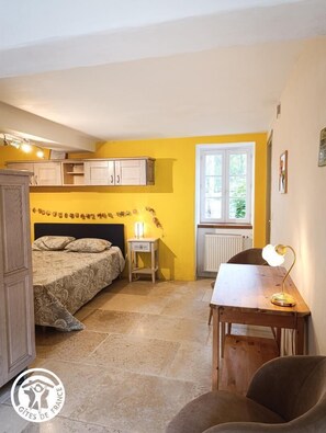 Habitación pequeña con cama, una mesita de noche con lámpara, ventana y radiador.