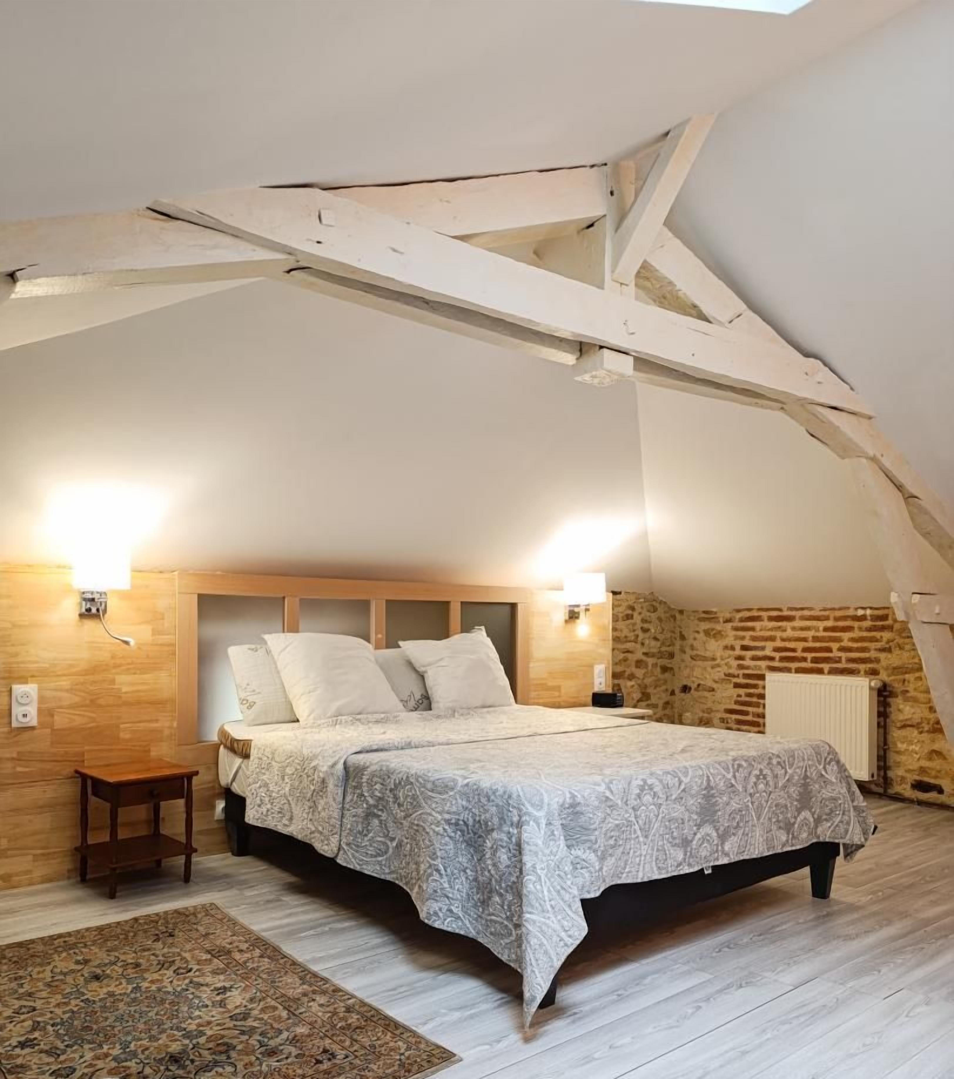 Une chambre à coucher avec un lit, des lampes de chevet, une petite table de nuit en bois et un tapis à motifs.