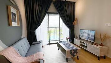 Una sala de estar moderna con sofá, televisor y vistas al balcón.
