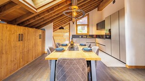 Un espace repas avec une table en bois, des chaises et une lucarne au-dessus.