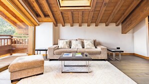 Un salon chaleureux avec un plafond en bois, un canapé, une table basse et une vue sur le ciel grâce à une lucarne.