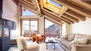 Un salon chaleureux avec un plafond en bois, un canapé, un fauteuil et une table basse.