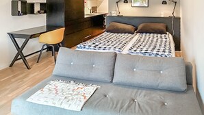 A modern bedroom with a bed, grey sofa, desk, and chair.