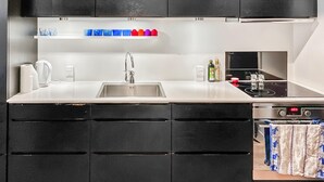 A modern kitchen with black cabinets, a stainless steel sink, and a built-in stove.