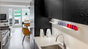 A modern kitchen with black cabinets, a white countertop, and a built-in shelf with colorful mugs.