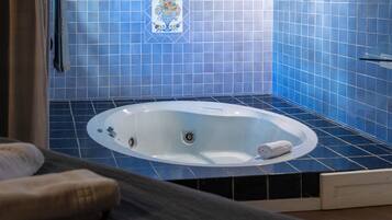 Un baño con bañera, azulejos azules y una toalla sobre el mostrador.