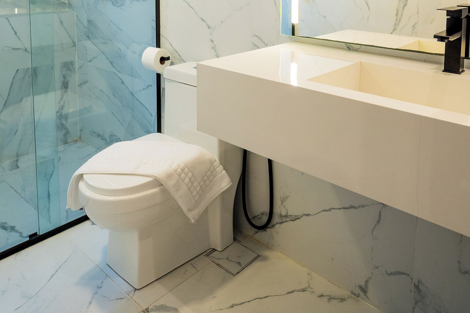 Un baño moderno con inodoro, lavamanos y espejo.