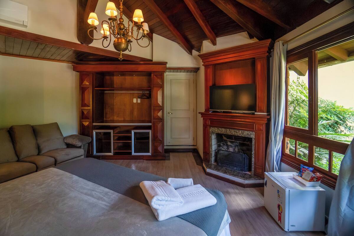 Une chambre à coucher avec un lit, une télévision, une cheminée et une fenêtre donnant sur un beau paysage.